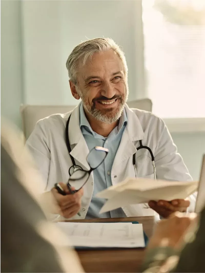 Médico con guardapolvo y estetoscopio conversando con un paciente
